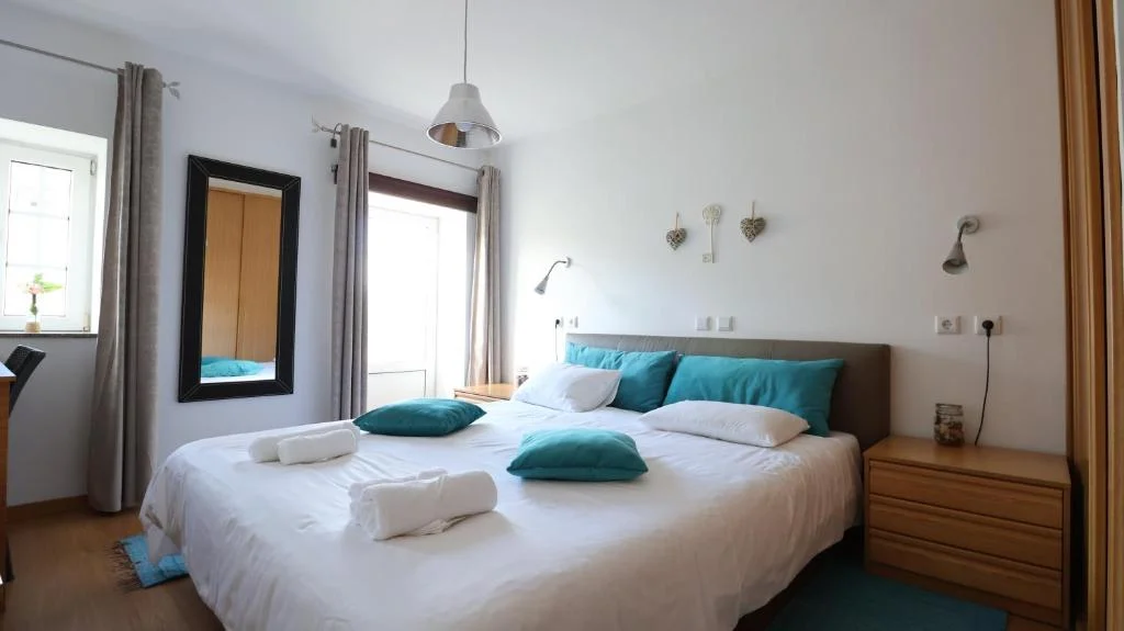 Quarto Turquesa com cama de casal, luz natural, decoração clara e ambiente acolhedor